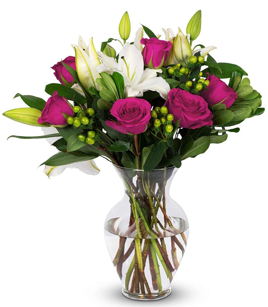 Glass vase containing fresh cut roses and other flowers